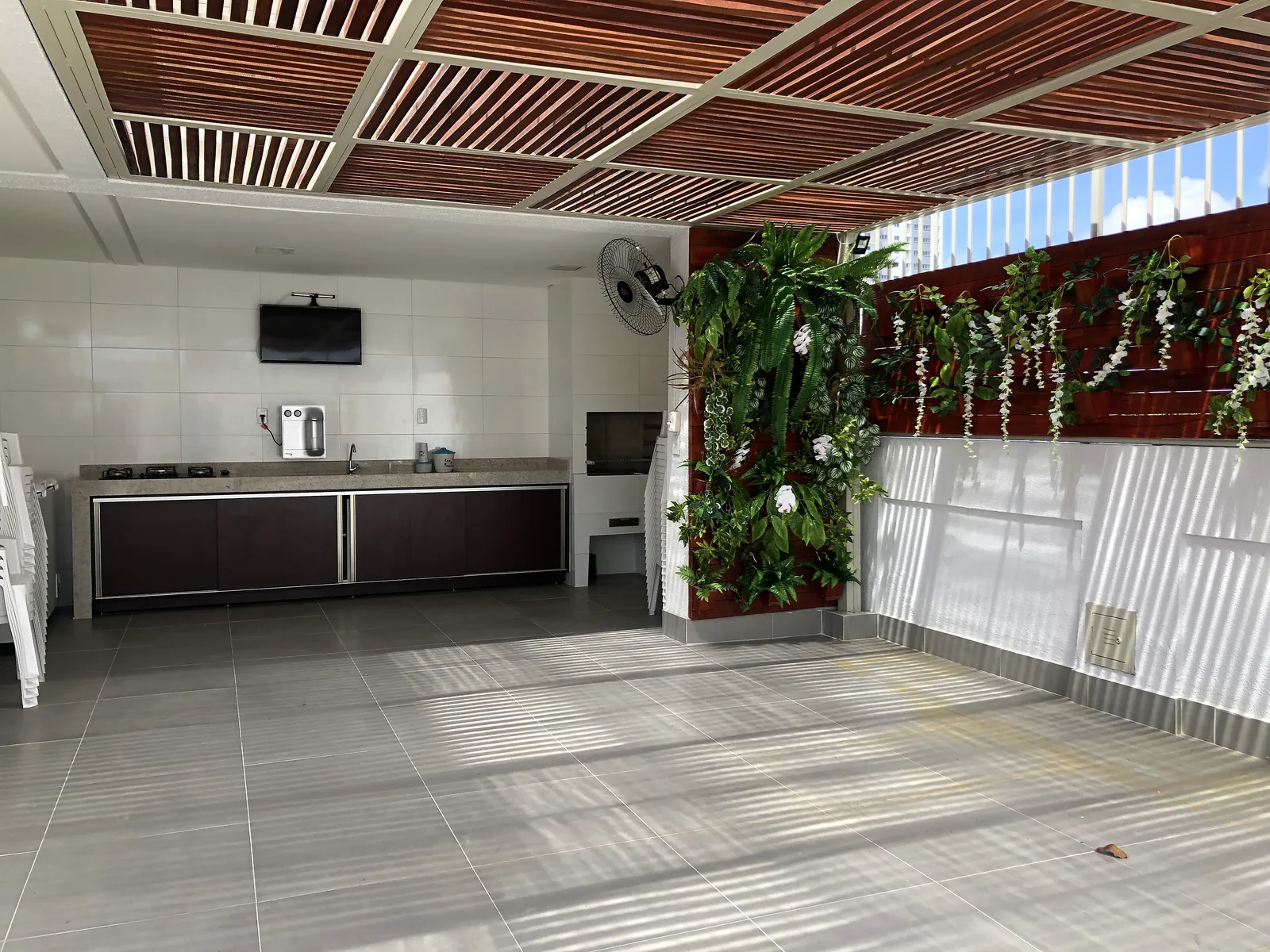 Espaço gourmet com bancada, marcenaria e jardim vertical